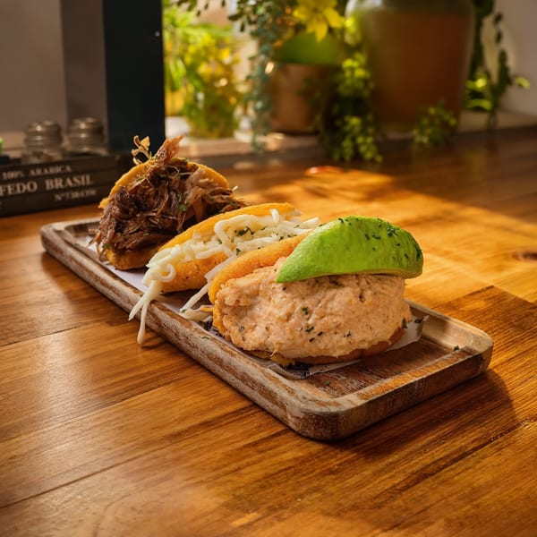 Two gourmet sandwiches on a wooden serving board, including a breaded chicken sandwich topped with avocado and a shredded meat sandwich.